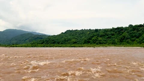 Scenic view of a flowing river with lush green hills under a cloudy sky in .. Stock-Footage 339369305
