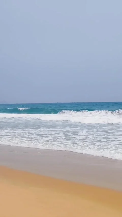 Scenic view of gentle ocean waves rolling onto a sandy beach Vidéo 334084795
