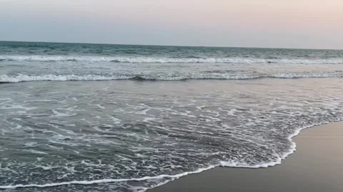 Scenic view of gentle ocean waves rolling onto a sandy beach at sunset Vidéo 334163182