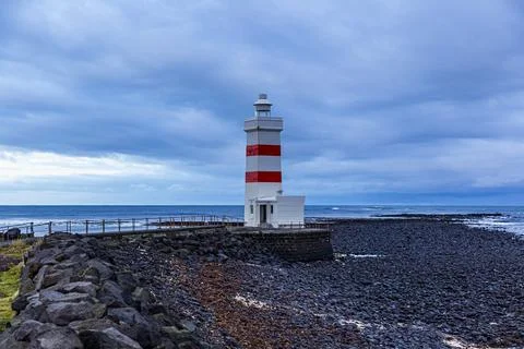 Scenic view of an idyllic old lighthouse near a black rock beach Stock Photos