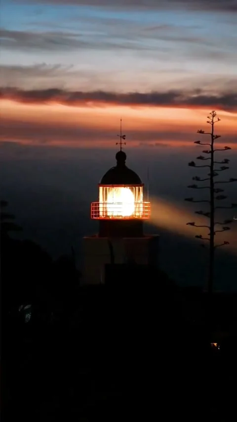 A scenic view of a lighthouse beacon rotating against a vibrant Stock Footage 337322957