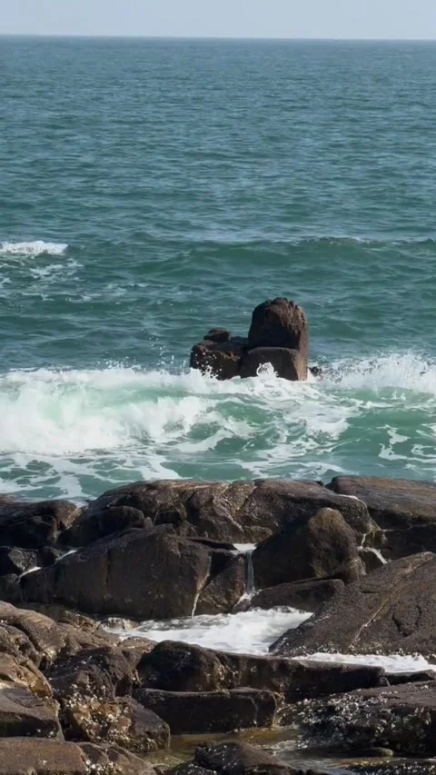 Scenic view of a lone rock formation surrounded by ocean waves at the shoreline Vidéo 334084065