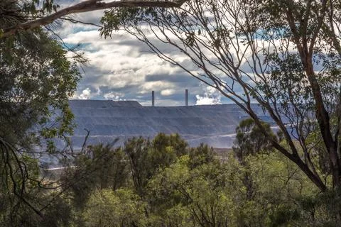 Scenic view looking through trees toward a large open cut coal mine Stock Photos