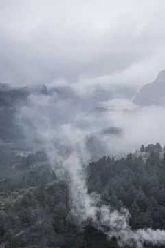 Scenic view of mountain against dramatic sky during foggy weather. Vertical i Stock Photos