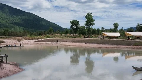 Scenic View of Mountain Lake with Rustic wooden rowboat and Bungalow in Cambodia Stock Footage 336781224