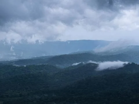 Scenic view of mountain range covered with white fog and mist under cloudy sk Stock Photos