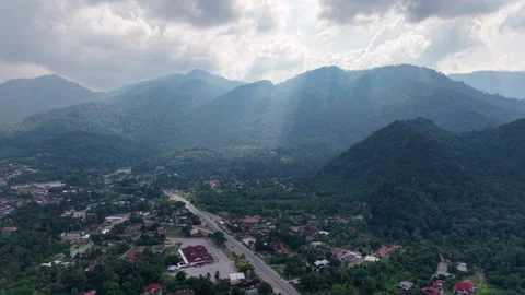 Scenic View of Mountain Range with Village Road and Cloud Rays in Daylight Stock Footage 339841495