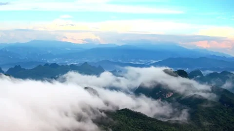 A scenic view of mountains shrouded in clouds under a blue sky Stock Footage 312304096