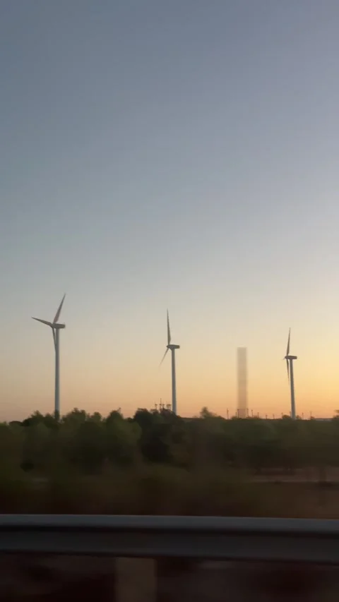Scenic view from a moving car window showing a field of wind turbines spinning Stock Footage 345424751
