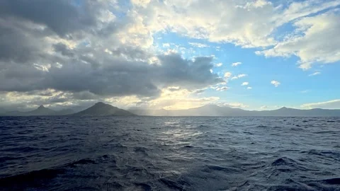 Scenic view of the ocean with mountains in the background under a dramatic Stock Footage 340635191