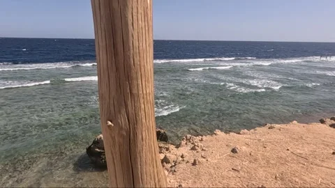 A Scenic View of the Ocean Waves and Coastal Landscape Framed by a Weathered 库存影片 330103622