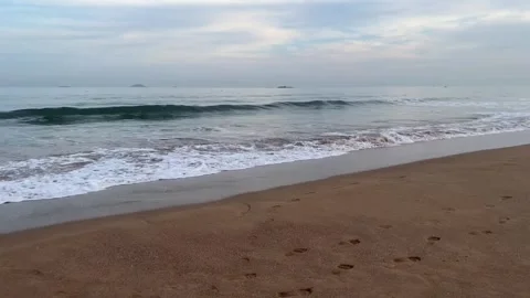 Scenic view of ocean waves crashing on the sandy beach at sunset Stockbeeldmateriaal 334163392