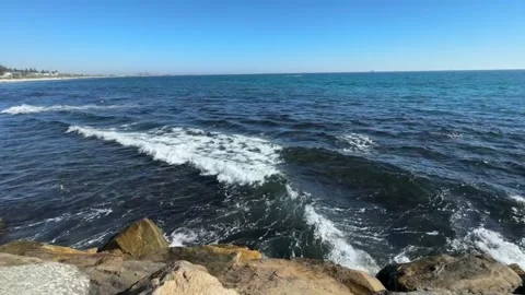 Scenic view of the ocean waves crashing against rocky shoreline on a sunny day Vídeos de archivo 334164052