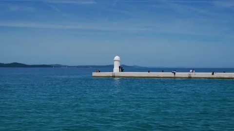 Scenic view over blue sea to the white lighthouse on Zadar Riva pier with Vídeo Stock 342354330