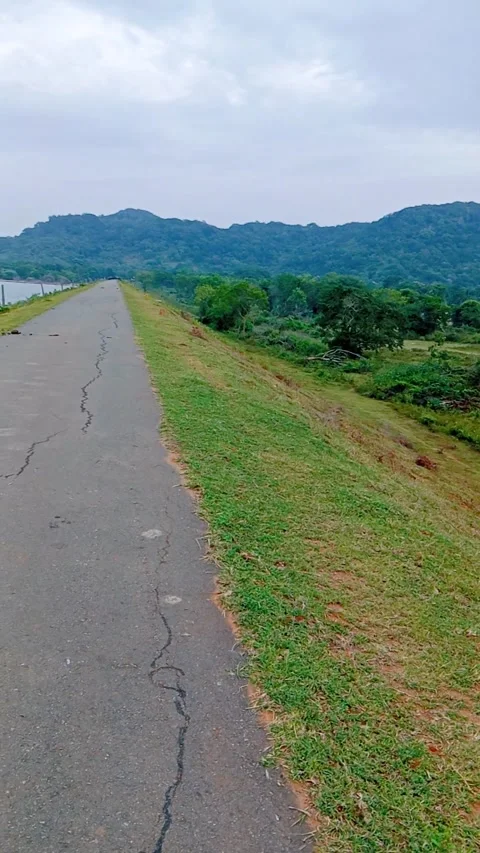 Scenic view of a paved road along a lake and green hills landscape Stock Footage 346273208