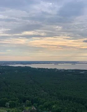 Scenic view of river and forest under cloudy sky at sunset Stock Photos