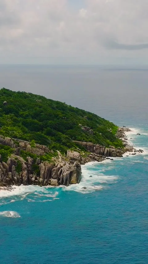 Scenic view of rocky cliffs and lush vegetation by the sea. La Digue, Seychelles Stock Footage 311608057