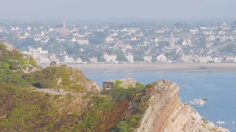 A scenic view from a rocky, vegetation-covered cliff featuring a historic stone Stock Footage 346665031