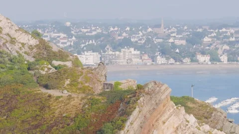 A scenic view of the rugged cliffs and rocky slopes of Cap dErquy with lush Stock Footage 346665372