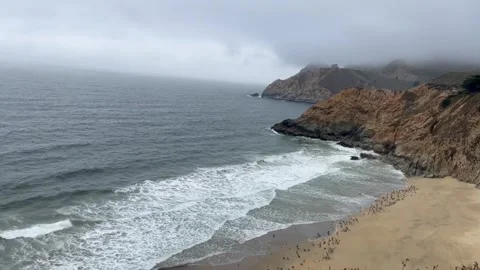 Scenic view of a sandy beach and rugged coastal cliffs on a cloudy day Vídeos de archivo 334084079