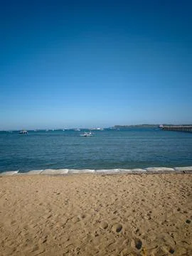 Scenic view of sandy beach, calm blue sea, and horizon under clear sky Stock Photos
