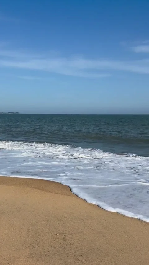 Scenic view of a sandy beach with gentle ocean waves rolling onto the shore Vidéo 334163304