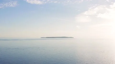 Scenic view of small flat island on a sea horizon on bright sunny day Stock-Footage 140095409