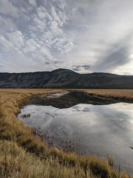 Scenic view of a small pond inside a valley surrounded by hills and mountains Stock Photos