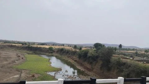 Scenic view of a small river flowing through rural landscape in India, with gree Stock Photos
