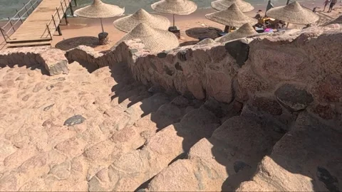 A Scenic View of Stony Steps Leading to a Serene Beach with Umbrellas, Capturing 库存影片 330099352