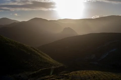 Scenic view of sun shining over mountains against sky Stock Photos