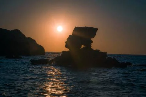 Scenic view of sunset between rocks and waves on a greek Island, cyclades Stock Photos