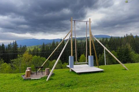 A Scenic View of a Swing Set Surrounded by Lush Greenery and Dramatic Clouds in Stock Photos