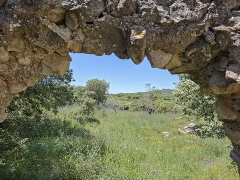 Scenic view through ancient stone window showing a lush meadow and distant .. Foto stock