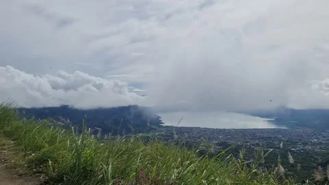 A scenic view of a town nestled between a lake and mountains, under a cloud.. Stock Footage 291379656