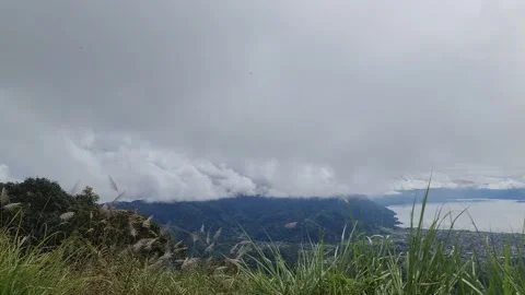 A scenic view of a town nestled between a lake and mountains, under a cloud.. Stock Footage 291380974