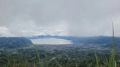 A scenic view of a town nestled between a lake and mountains, under a cloud.. Stock Footage 291381102