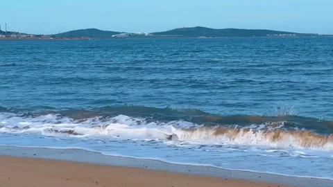 Scenic view of a tranquil beach with gentle waves rolling onto the sandy shore Vidéo 334163104