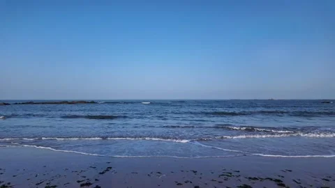 Scenic view of a tranquil beach with gentle waves and rocky coastline under a Stockbeeldmateriaal 334163774