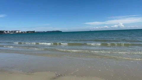 Scenic view of a tranquil sandy beach with calm waves and a distant coastline Vidéo 334163727