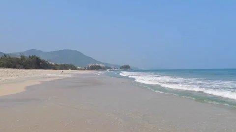 Scenic view of a tranquil sandy beach with rolling waves and distant mountains Vídeos de archivo 334163876