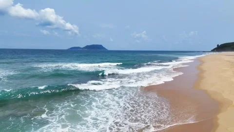 Scenic view of a tropical beach with waves and a distant island Vídeos de archivo 334084457