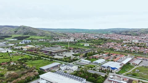 Scenic view of urban development and green spaces in a town surrounded by hills Stock Footage 342476166