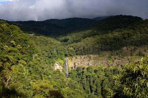 A scenic view of a waterfall cascading down a lush, green forested mountainside 스톡 사진