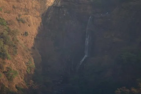 Scenic view of a waterfall cascading down a deep valley surrounded by rocky Stock Photos