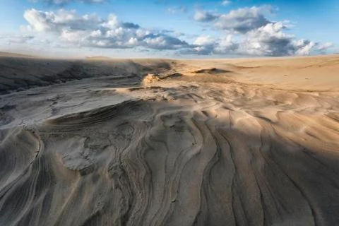 Scenic view of wave pattern on sand at beach against cloudy sky Stock Photos