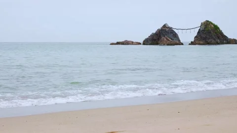Scenic view of waves breaking on sandy beach with Meoto Iwa rocks in Japan Stock Footage 338194045