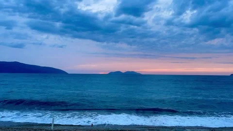 Scenic view of waves rushing at sandy beach against sky during sunset Stock Footage 284078916