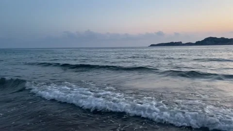 Scenic view of waves rushing at sandy beach against sky during sunset Stock Footage 284229049