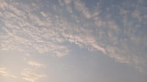 Scenic view of white clouds scattered across a bright blue sky at sunset. Stock Photos